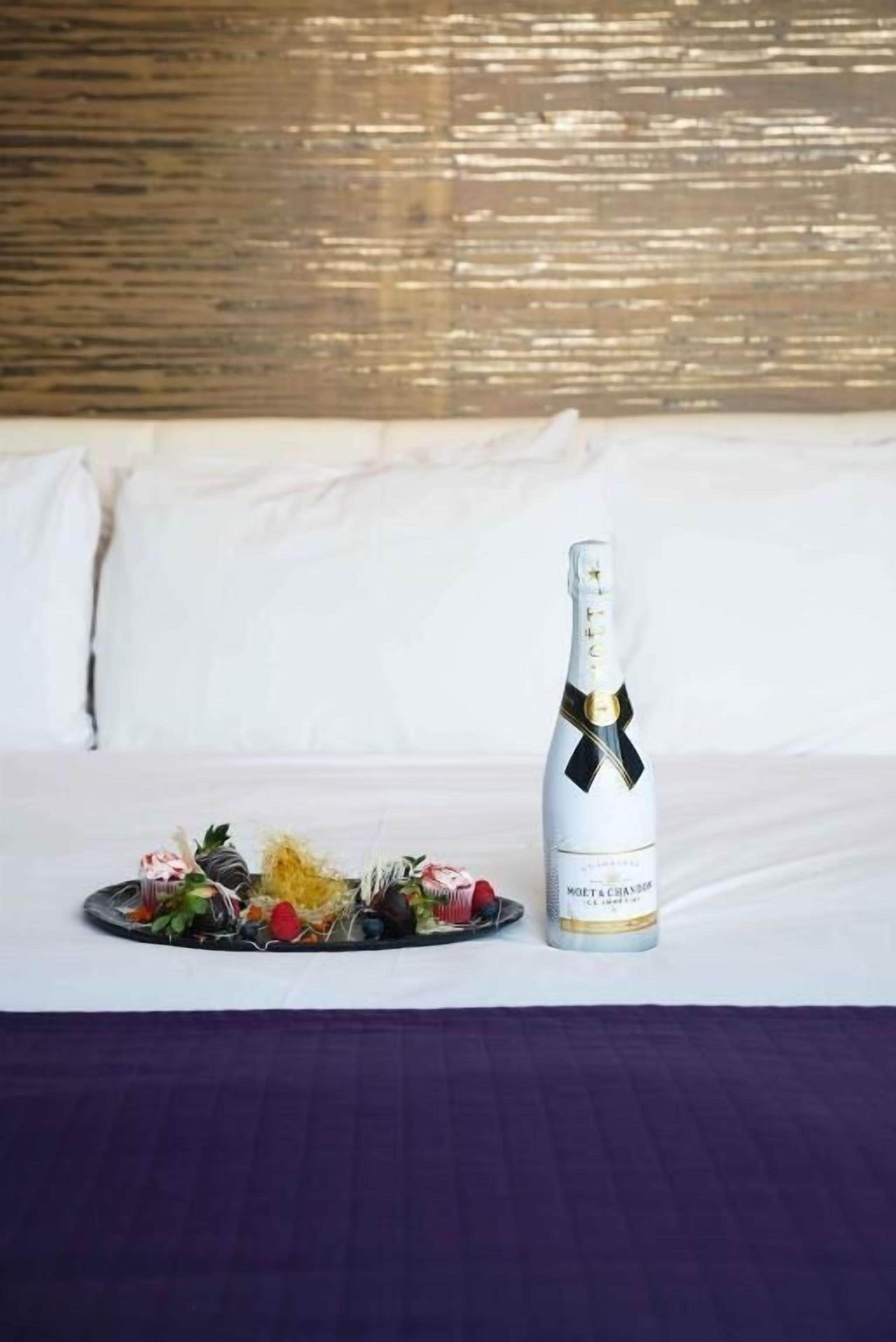 A bottle of Moët & Chandon champagne on a table with a purple tablecloth, surrounded by a variety of fruits and chocolates.