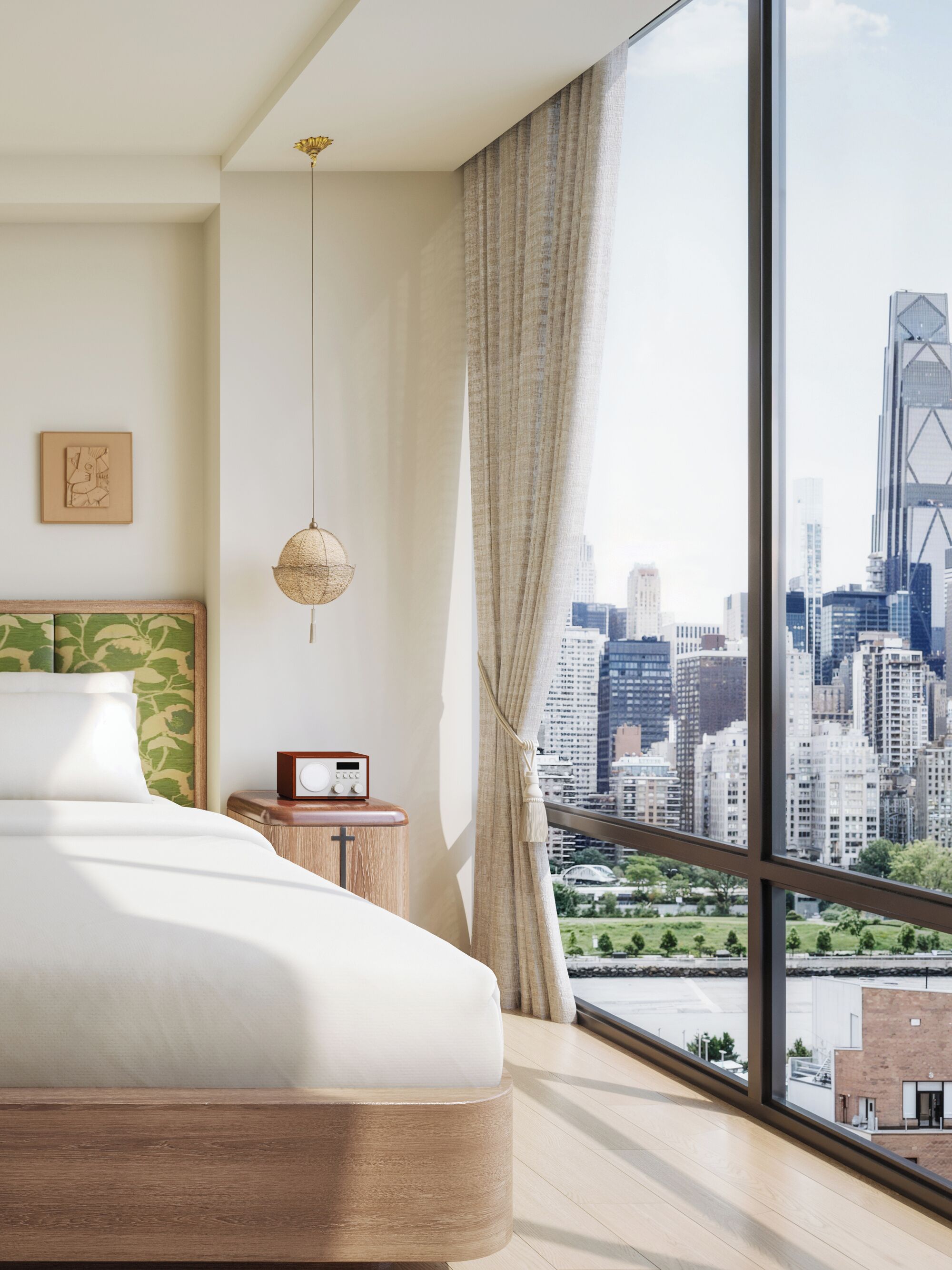 A modern bedroom with a city view, a bed, a bedside table with a radio, and a hanging light fixture.
