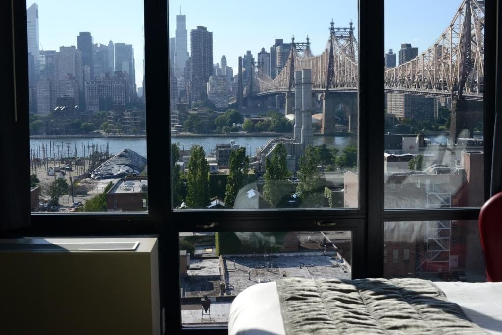 Ein Zimmer mit großem Fenster und Blick auf eine Stadtlandschaft, eine Brücke und einen Fluss.