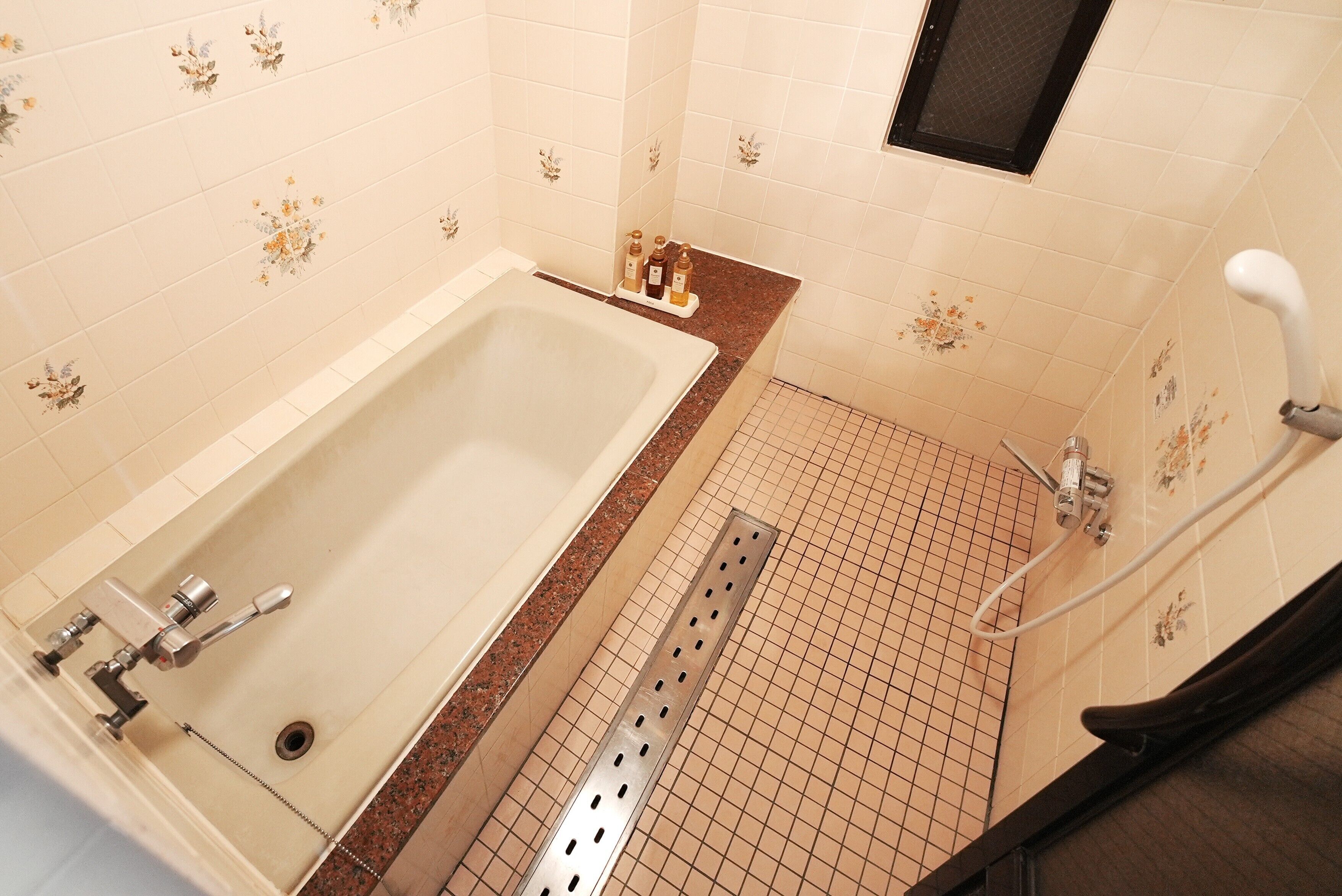 A bathroom with a bathtub, a shower, and a hand shower.