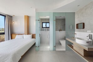 A modern hotel room with a bed, a bathroom with a shower, and a large window.
