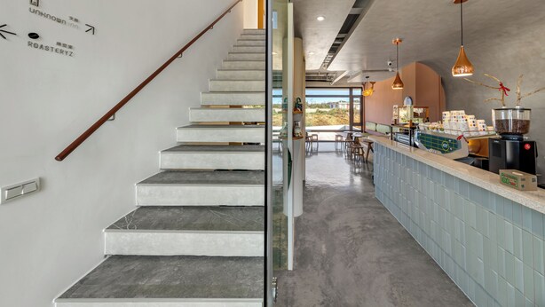 A modern interior with a staircase, a bar area, and a view through a glass wall. - Unknown Coffee Inn (Liuqiu)