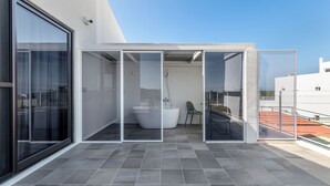 A modern balcony with a glass enclosure, a white bathtub, and a green chair. - Unknown Coffee Inn (Liuqiu)