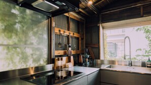 A modern kitchen with a stainless steel countertop, wooden cabinets, and a built-in stove. - Ivy Place Harajuku Urban Steel Teahouse (Tokyo)