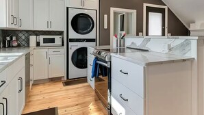 Une cuisine de taille réduite avec des meubles blancs, un four à micro-ondes, un four encastré et un ventilateur de plafond.