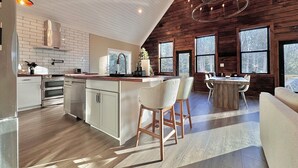 Een moderne keuken met een centraal eiland, houten wanden en grote ramen.