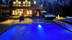 Een houten huis met twee verdiepingen, een balkon, een zwembad en een jacuzzi.