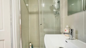 A bathroom with a glass-enclosed shower, a white sink, and a mirror.