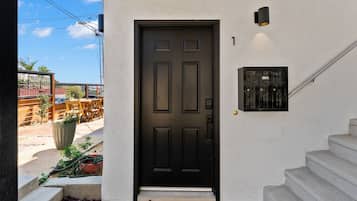 A black door with a mailbox and a number plate on the wall.