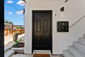 Una puerta negra con un buzón y una placa con número en la pared.