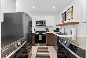 Una cocina compacta con lavadora y secadora integradas, microondas, estufa y fregadero.