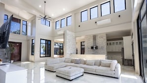 A spacious living area with a large sectional sofa, a kitchen in the background, and a high ceiling with skylights. - Bullock Island, Belize (Placencia)
