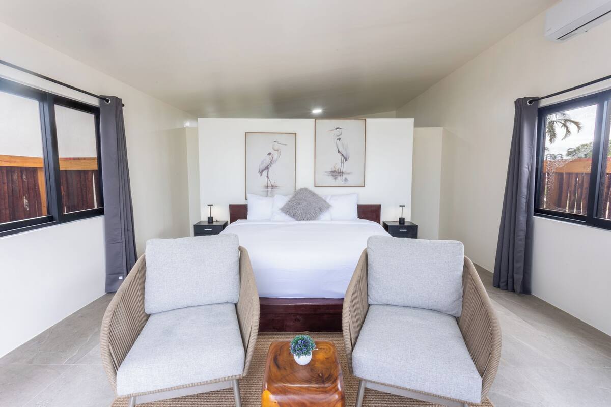 Une chambre d’hôtel comprenant un lit, deux fauteuils, une petite table basse et deux œuvres d’art encadrées accrochées au mur.