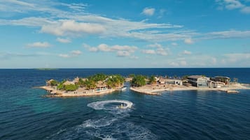 A coastal resort with multiple buildings, a marina, and a small island with palm trees.