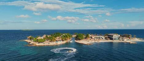A coastal resort with multiple buildings, a marina, and a small island with palm trees.