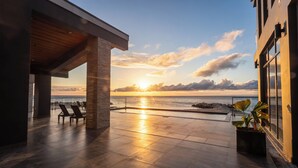 A terrace with a sunset view, lounge chairs, and a potted plant. - Bullock Island, Belize (Placencia)