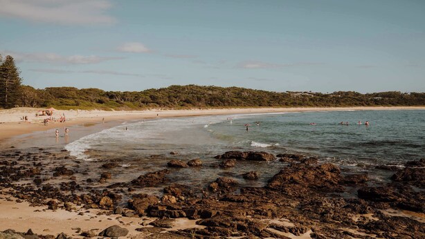 A beach with rocky shoreline, clear water, and a sandy beach. - Three-Kalm by Tiny Away (Rainbow Flat)
