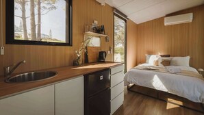 A modern kitchen with a sink, a coffee maker, and a window with a view of trees. - Three-Kalm by Tiny Away (Rainbow Flat)