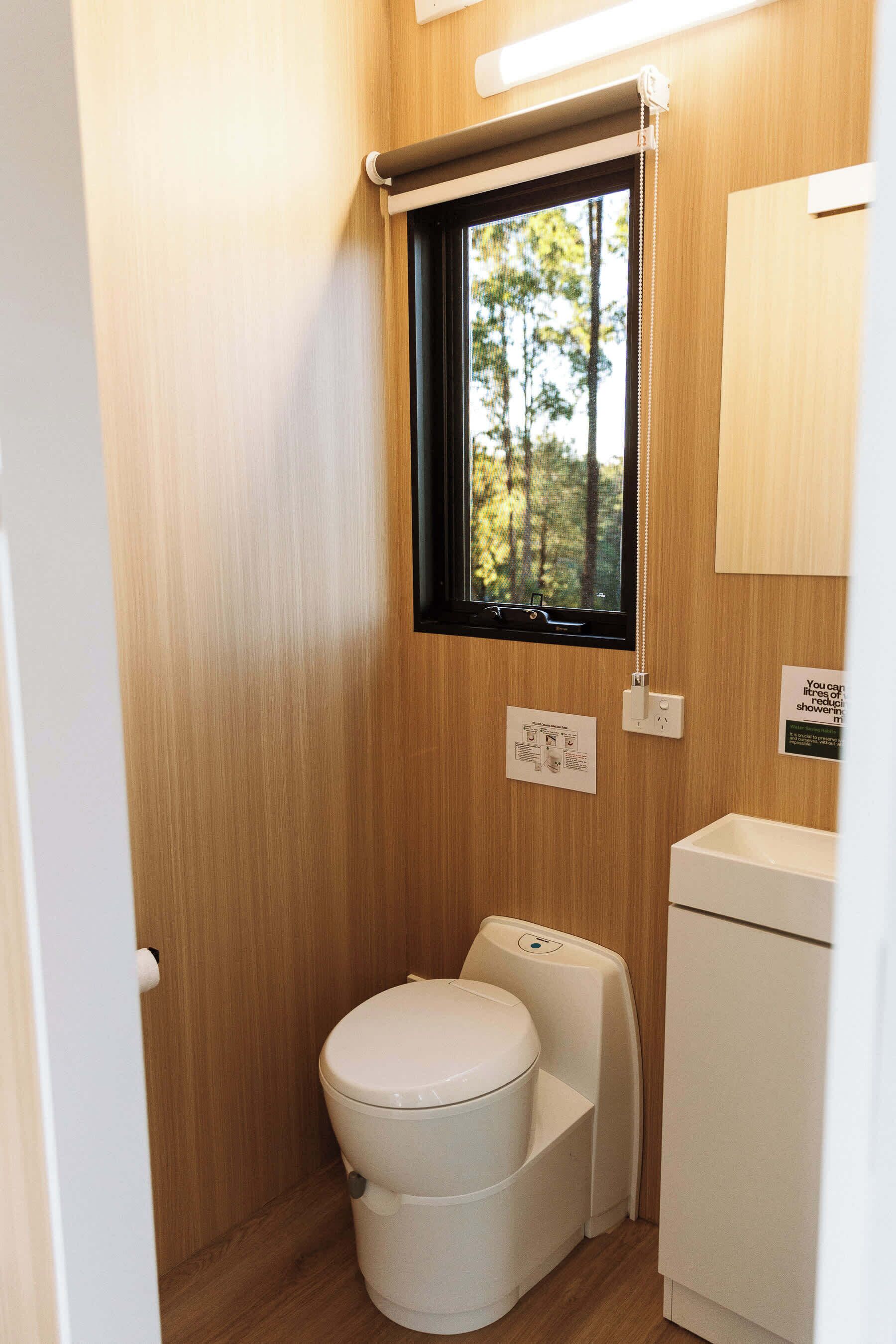 Et lille badeværelse med toilet, et vindue og en vask.