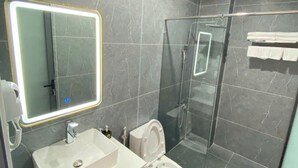 A modern bathroom with a glass-enclosed shower, a white sink, and a toilet. - Golden Hotel SG by BAY LUXURY (Ho Chi Minh City)