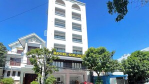 A hotel named 'HOTEL GOLDEN' with a modern facade, a parking area, and a small adjacent structure. - Golden Hotel SG by BAY LUXURY (Ho Chi Minh City)
