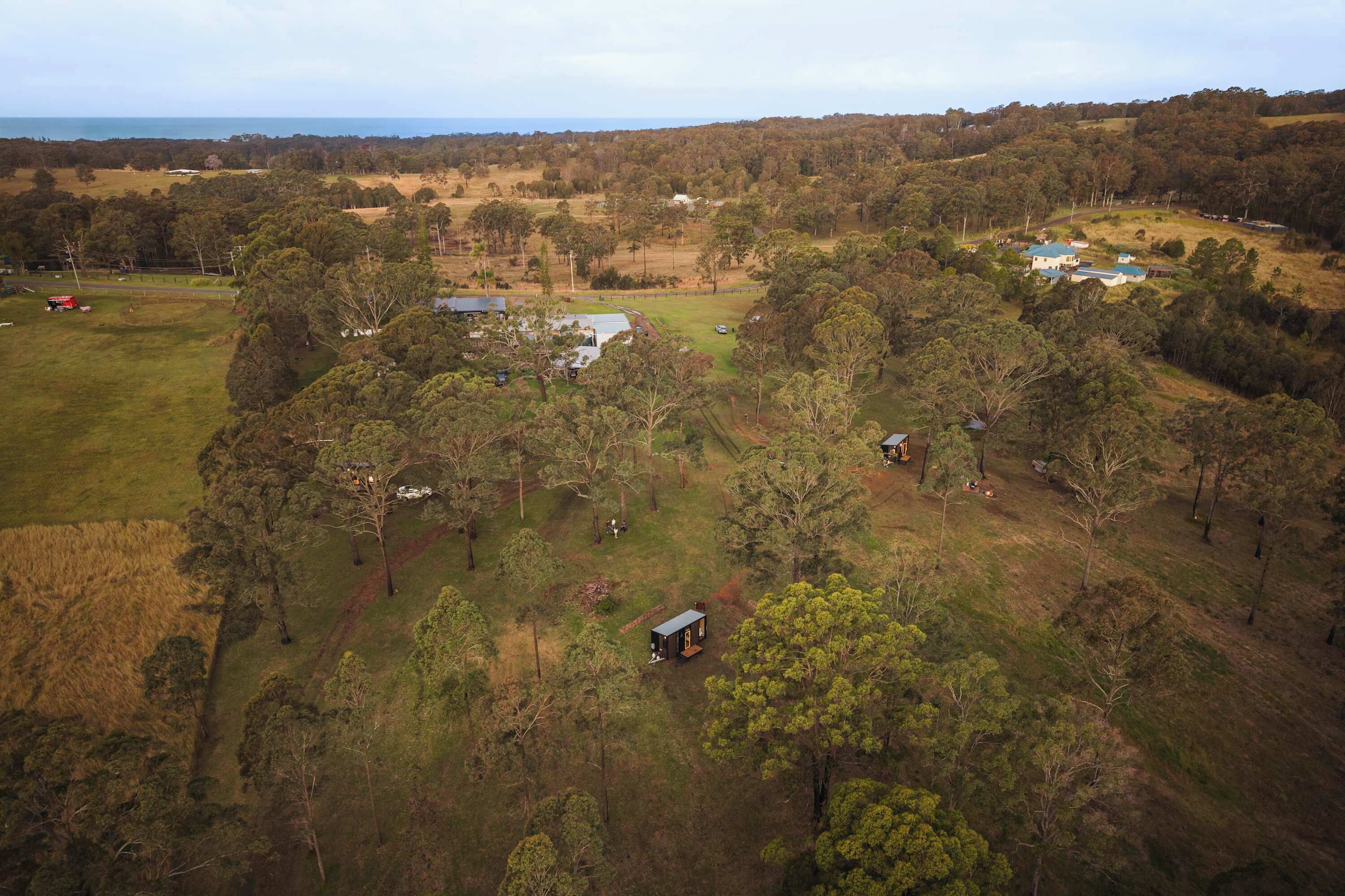 A rural landscape with scattered buildings, a large open field, and dense forest areas.
