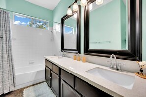 Un baño con bañera, dos lavamanos, un espejo grande y una ventana.