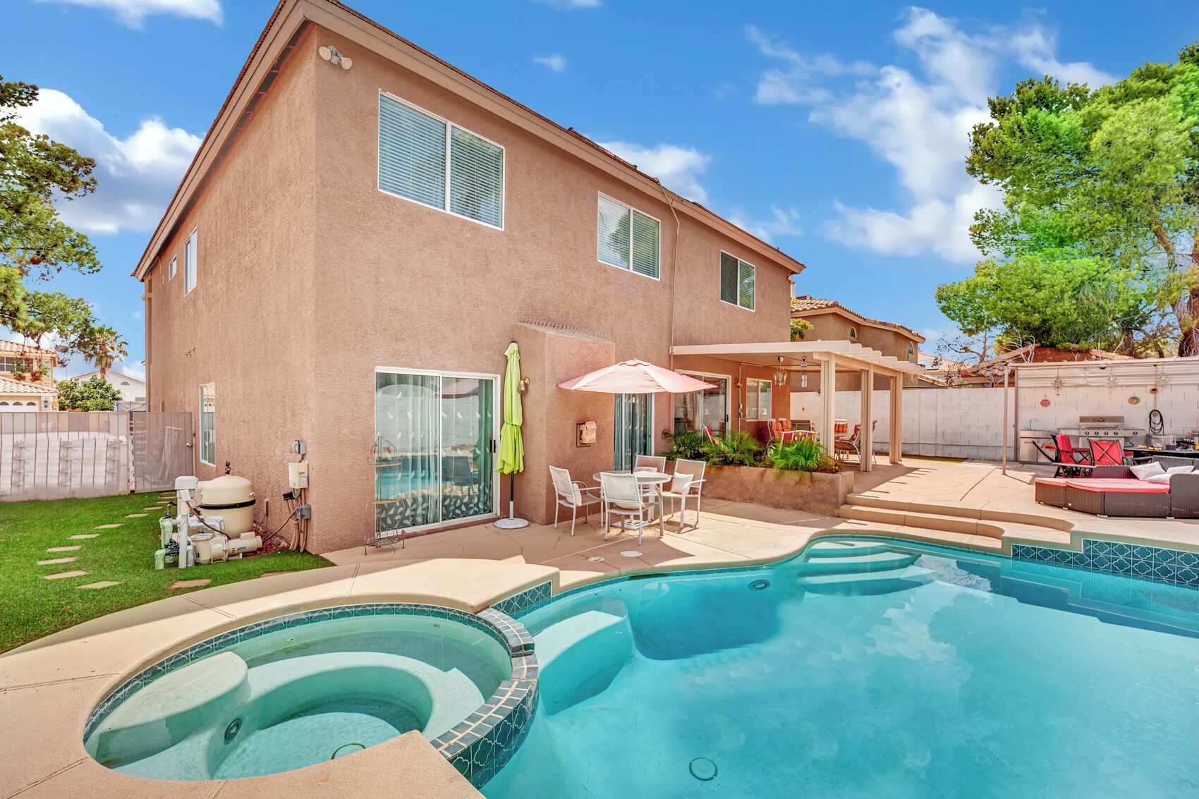 A two-story house with a swimming pool, outdoor seating, and a barbecue area.