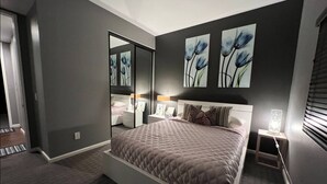 Ein Schlafzimmer mit einem Bett, Nachttischen, einem Spiegel und Bildern an der Wand.