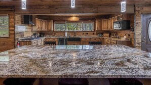 A kitchen with wooden cabinets, granite countertops, and pendant lighting. - Mountain cabin w/ deck & lake access (Terra Alta)