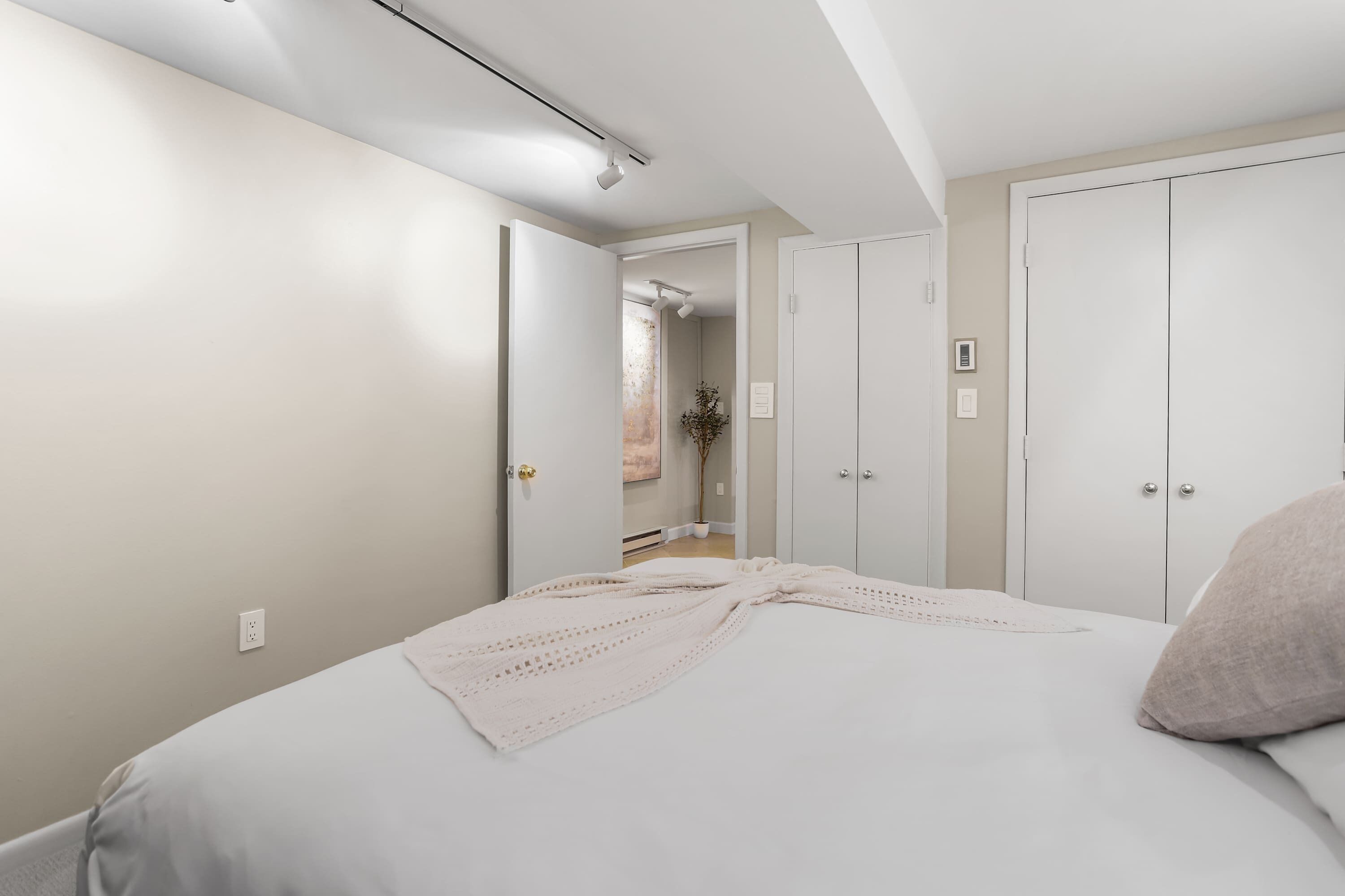 A bedroom with a bed, a wardrobe, and a door leading to another room.