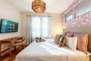 A bedroom with a bed, a desk, a TV, and a window with curtains. - Fall in Nashville: rooftop skyline views near Broadway, sleeps 12 (Nashville)
