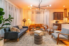 A modern living room with a sofa, armchairs, a coffee table, and a dining area. - Nashville rooftop, karaoke garage & game room house, sleeps 12 near downtown (Nashville)