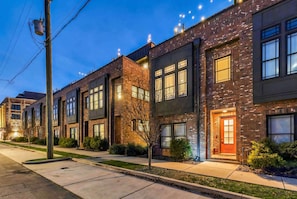 A row of modern brick townhouses with large windows and a well-lit entrance. - Nashville rooftop, karaoke garage & game room house, sleeps 12 near downtown (Nashville)