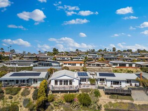 Um bairro residencial com casas modernas, painéis solares e um céu azul límpido.