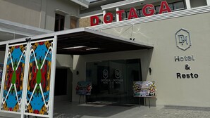 L'esterno dell'Hotel & Resto DOTAGA, con un ingresso ben visibile e un pannello decorativo colorato di fronte.