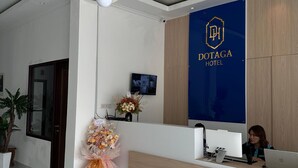 Una reception hotel dal design moderno, un'area accoglienza e un logo a parete.