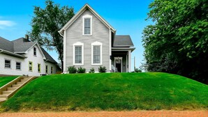 A two-story house with a front porch, a brick pathway leading to the entrance, and a well-maintained lawn. - Hot Tub~Gym~5 Min to Mass Ave~Backyard Retreat~Indianapolis (Indianapolis)