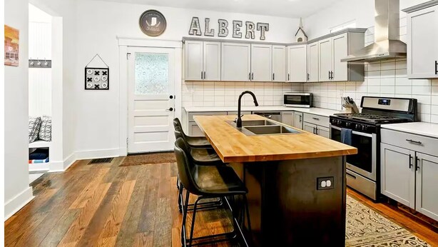 A modern kitchen with white cabinets, a wooden island, and a stainless steel stove. - Hot Tub~Gym~5 Min to Mass Ave~Backyard Retreat~Indianapolis (Indianapolis)