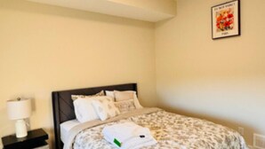 A bedroom with a bed, a nightstand, a lamp, and a ceiling light. - Beautiful walk out basement suit in south east Calgary (Calgary)