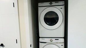 A laundry room with two stacked front-loading washing machines. - Beautiful walk out basement suit in south east Calgary (Calgary)
