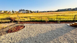 A gravel patio with a metal planter and a wooden bench. - Beautiful walk out basement suit in south east Calgary (Calgary)