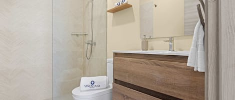 Et moderne badeværelse med bruser, toilet og vask.