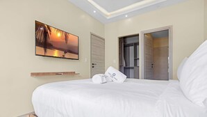 A bedroom with a bed, a TV mounted on the wall, and a closet with sliding doors. - Cozy 1 BR Apartment by Vistacana (Punta Cana)
