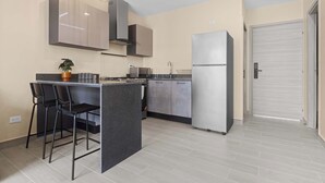 A modern kitchen with a central island, bar stools, stainless steel appliances, and pendant lighting. - Cozy 1 BR Apartment by Vistacana (Punta Cana)