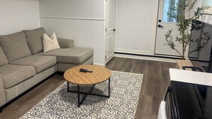 A living room with a sectional sofa, a round coffee table, and a patterned rug. - Haddock Heights (Williams Lake)
