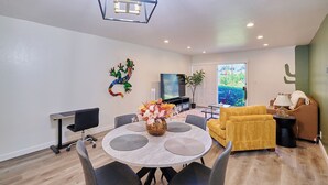 Un salon moderne comprenant un coin repas, un canapé, un téléviseur et une décoration à base de cactus.