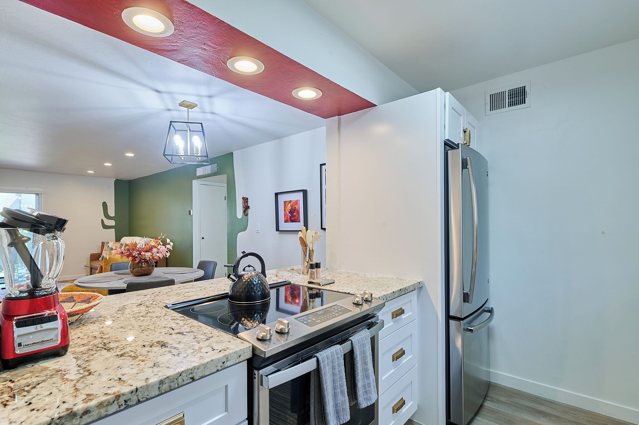 A modern kitchen with a built-in stove, a refrigerator, and a dining area with a table and chairs.