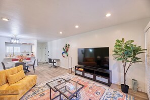 A modern living room with a sofa, a coffee table, a TV, and a potted plant. - Scottsdale Escape - 3 Bed Condo in Old Town Scottsdale! (Scottsdale)