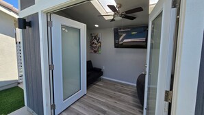 A modern interior with a sliding glass door leading to an outdoor area, a ceiling fan, and a painting on the wall.